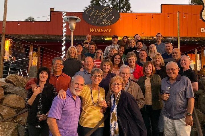 The whole crowd raising glasses outside the winery at dusk
