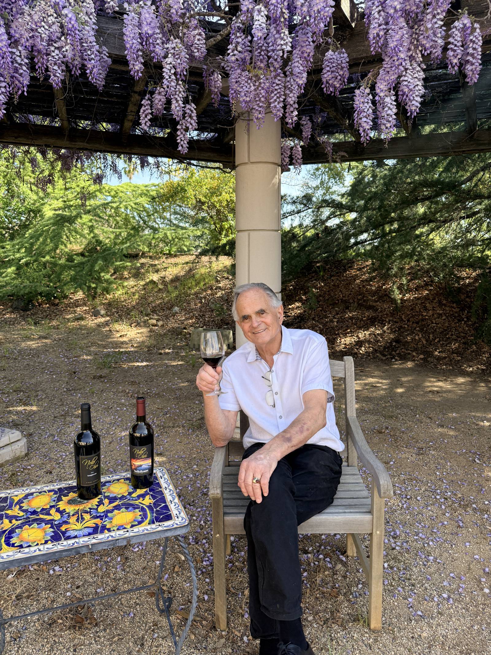 Nello with a glass under the wisteria