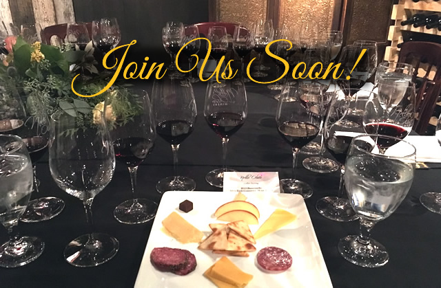 Cheese, charcuterie and fruit plate surrounded by wine glasses.