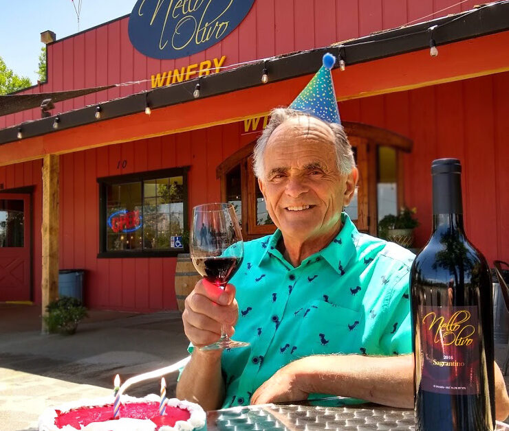 Man in birthday hat with wine glass sitting at table outside