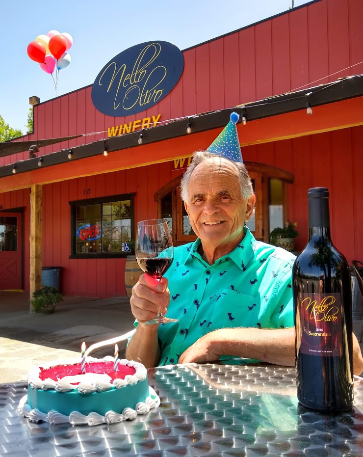 Man in birthday hat with wine glass sitting at table outside